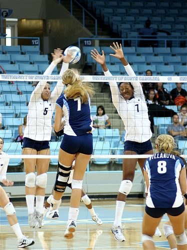 A Villanova hitter in volleyball aims for the seam, the hole in the block between the two Chapel Hill blockers.