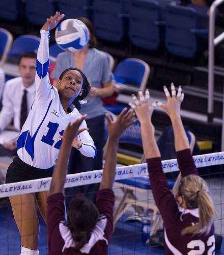 Volleyball Skills Attack Strategies: Using the block Creighton hitter aiming for the blockers outside hand (Photo White and Blue Review)