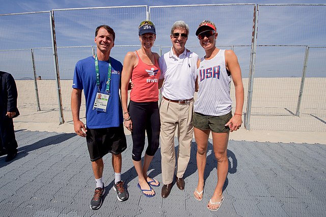 U.S. Secretary of State John Kerry poses for a photo with U.S. Olympic women's beach volleyball players Kerri Walsh and April Ross, and their coach Marcio Sicoli, on the Copacobana beach in Rio de Janiero, Brazil, on August 6, 2016, as he and his fellow members of the U.S. Presidential Delegation attend the Summer Olympics. [State Department Photo/ Public Domain] <a href="https://commons.wikimedia.org/wiki/File:Secretary_Kerry_Poses_for_A_Photo_with_U.S._Olympic_Beach_Volleyball_Players_Kerri_Walsh_and_April_Ross_(28750029891).jpg">U.S. Department of State from United States</a>, Public domain, via Wikimedia Commons