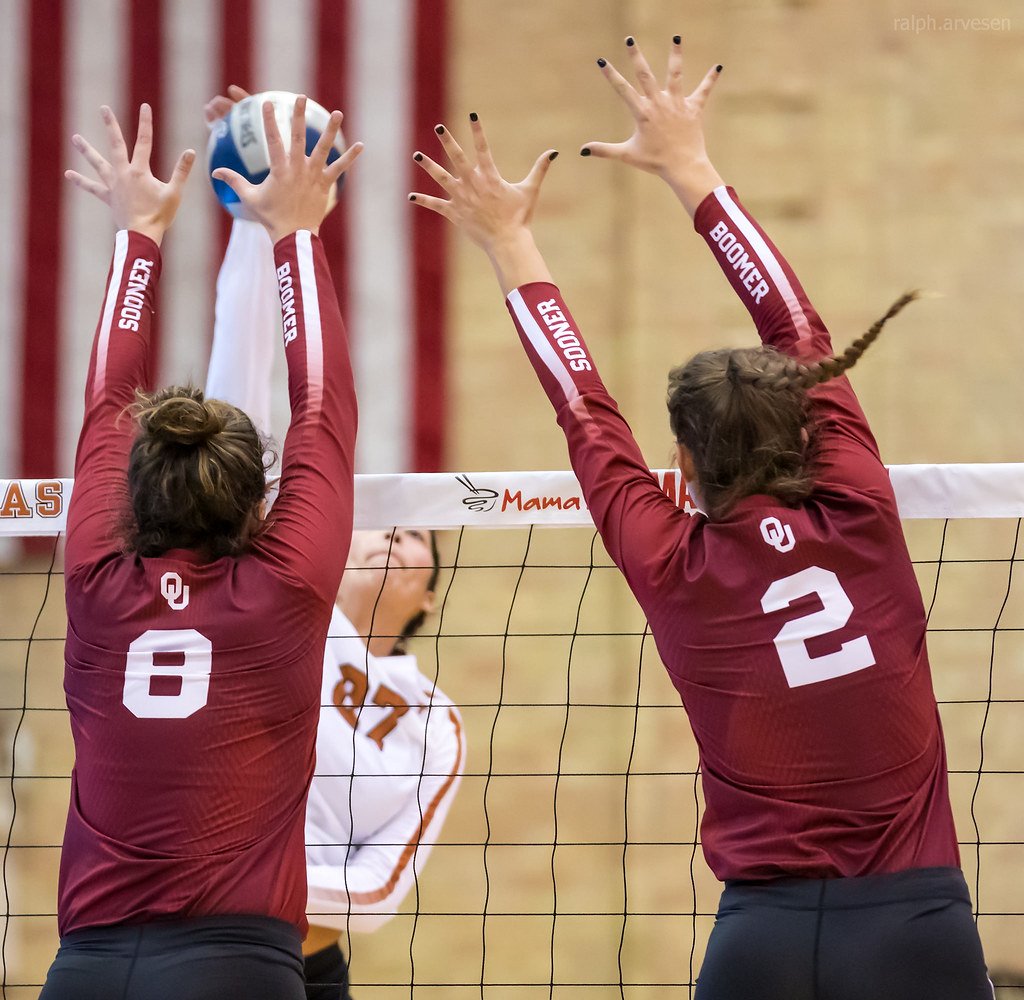 Oklahoma Sooners middle blocker (#2) travels laterally across the net to close the seam between her and her outside hitter volleyball player (#8) (Ralph Arvesen)