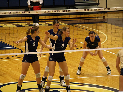 Blockers in ready volleyball position calling out the block. As a front row blocker on defense, you should never turn around to watch your server serve the ball. (Laurie T Mayers)