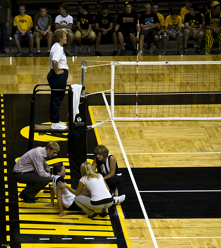 Volleyball officials:First referee waits while an injured players gets attended to.