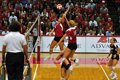 (John Carrel) Nebraska setter runs a double quick attack to her middle blocker and opposite hitter while opposing team blockers wait and watch.