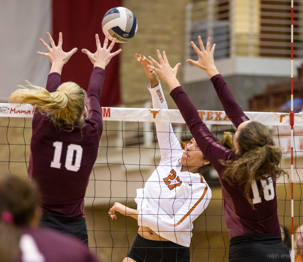 Texas A&M blockers take cross court against the Texas Longhorn outside hitter (Ralph Arvesen)